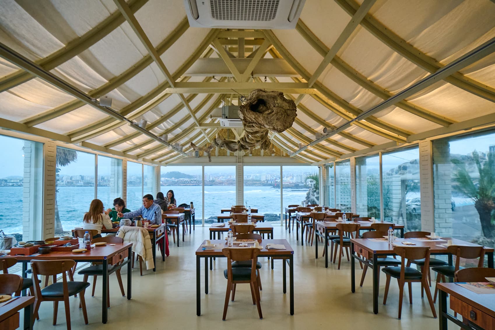 손님이 앉은 홀과 통창 너머 애월 바다